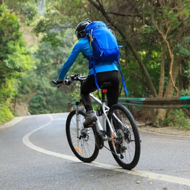 Cyclist biking through wooded area, Sri Lanka